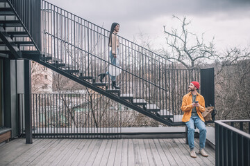 Man sitting on the steps, the girl going down on the bridge