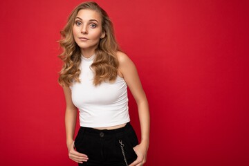 Portrait photo of young beautiful pretty self-confident assertive cool blonde woman with sincere emotions wearing stylish white top isolated over red background with free space