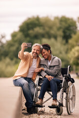 Adult man taking photo of him and his disabled woman.
