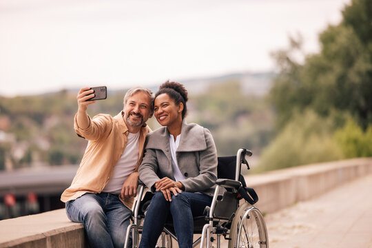 Woman in a wheelchair with husband, taking pictures.