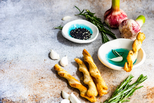 Grissini breadsticks with olive oil, garlic cloves, rosemary and sesame seeds