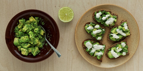 Preparing sandwiches with guacamole avocado spread and tahini and yoghurt dressing.