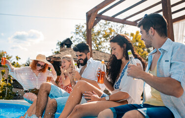 Group of friends having fun at summer vacation enjoying at poolside party.