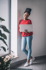 Black woman in red shirt with a laptop working remotely