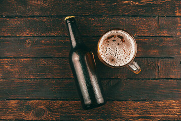 Top view photo of bottle beer and beer glass over wooden background
