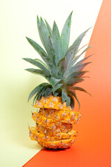 Sliced Victoria pineapple standing centered over a red and yellow background