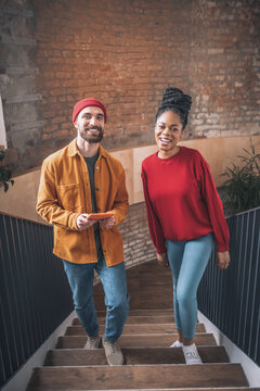 A man in a red hat and a black woman going upstairs