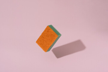 green-orange sponge hovers on a pink background. stock photo