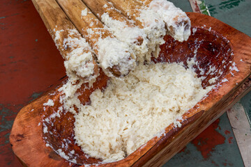 A group of people hammering glutinous rice with wooden sticks for making rice cakes with characteristics of Guangxi Zhuang nationality