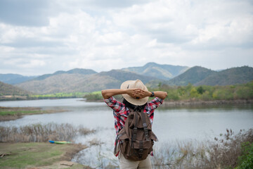 .woman raising hands up on the banks of the Lake / Asian woman hiker in front smiling happy, Woman hiking in woods, warm summer day.