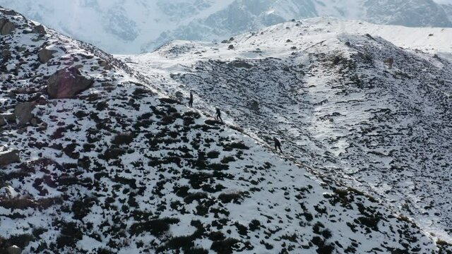 Hikers climbing snowy mountain towards Nanga Parbat basecamp, Himalaya