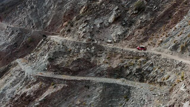 Red jeep driving on deadly mountain road to Fairy Meadows, Pakistan