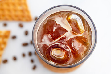 A cup of Iced Americano Coffee with ice cubes placed on a marble table in a coffee shop. Top view of a glass of coffee.