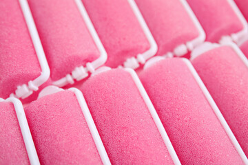 Many pink hair curlers as background, closeup