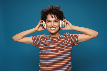 Fototapeta na wymiar Young curly laughing woman listening music with headphones