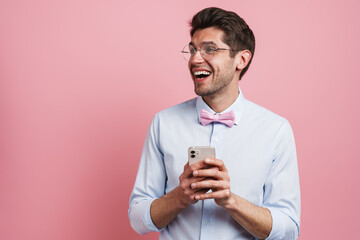 Young white man wearing bow tie laughing and using cellphone