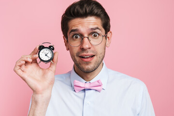 Young white man expressing surprise and showing alarm clock