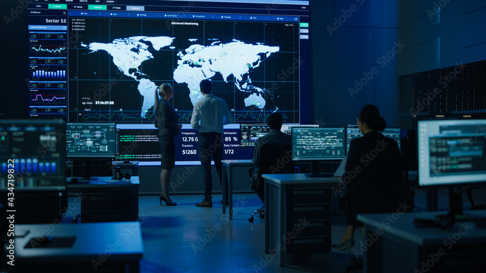 Leinwandbilder Project Manager Uses Digital Tablet Talks with Computer Scientist Looks at Big Screen Display Showing Infographics Global World Map Data. Telecommunications Control Control Room with People Working