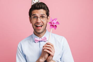 Young white man wearing party cone posing with flower wind spinner