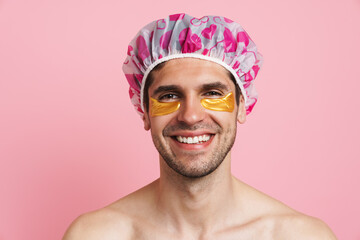 Young shirtless man wearing shower cap smiling and looking at camera