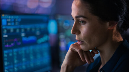 Confident Beautiful Middle Aged Woman Looks at Monitor Screens Focused. Professional Businesswoman...