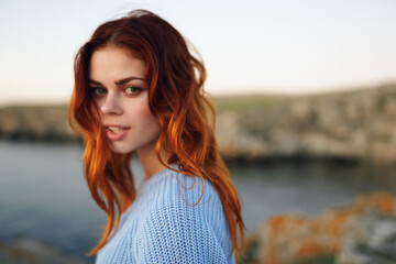 red-haired woman in sweater outdoors rocky mountains vacation