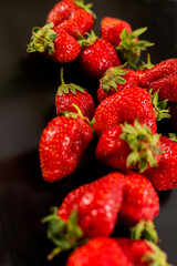 Red Strawberries a black plate. Natural fruits. White background.