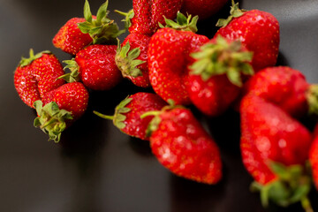 Red Strawberries a black plate. Natural fruits. White background.