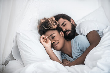 Obraz na płótnie Canvas Man hugging his wife sleeping in bedroom