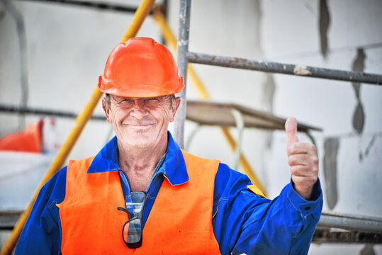 Senior manual worker with orange helmet showing thumbs up