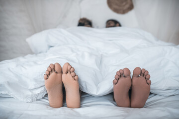 Husband and wife feet peeking out from under blanket