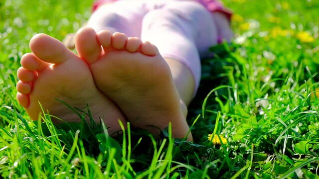 Child feet on the grass in summer. Selective focus.