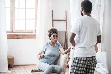 Upset wife sitting and husband standing with back