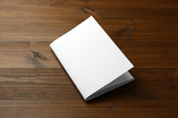 Blank paper brochure on wooden table. Mockup for design