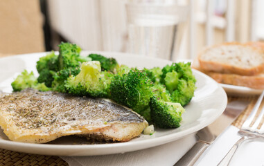 dish of fried dorado fish fillet with boiled broccoli
