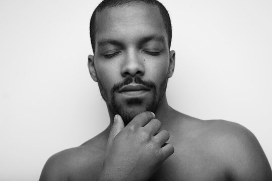 Black and white portrait of bald black man, touching his face. Isolated.