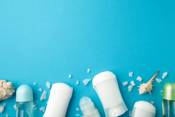 Deodorants for women and seashells on blue background with copy space