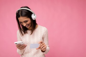 beautiful positive smiling young brunette woman wearing pink casual sweater isolated over pink...