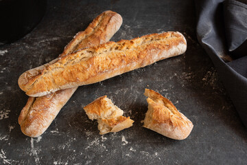Freshly baked french baguette on a black kitchen table with flour. Close-up.