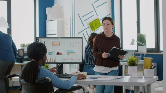Businesswoman discussing with invalid disabled paralysed african woman company development plan. Handicapped black leader explainig project strategy to manager corporate in strat up business office
