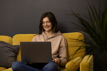 Cheerful laughing Attractive long-haired brunette girl Chatting and texting on laptop sitting on...