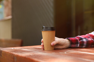 Fototapeta na wymiar Man with takeaway coffee cup at wooden table outdoors, closeup. Space for text