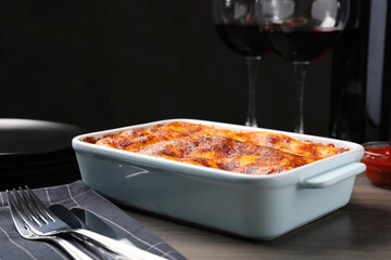 Tasty cooked lasagna in baking dish on wooden table