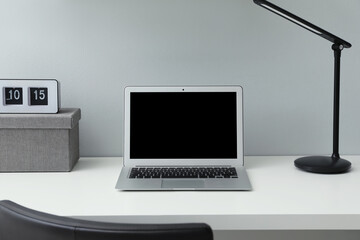 Modern laptop on white office desk indoors. Comfortable workplace