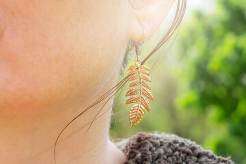 Outdoor detail of female ear wearing metal ornamental earring