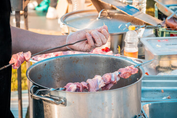 The hands of a man skewering meat on a skewer.