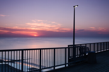 Fototapeta na wymiar SUNSET OVER THE SEASHORE - Evening walk to the pier