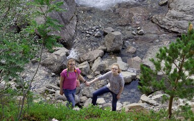 Two sisters, holding hands, climb the mountain