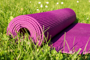 Yoga mat on green grass , close up. Outdoor sport equipment
