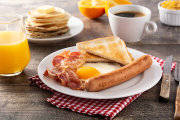 Traditional American breakfast with fried egg,toast,bacon and sausage on wooden table	